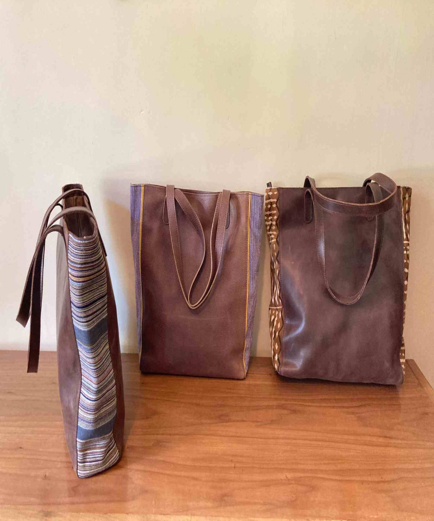 Borsa con pannelli laterali in pelle dalla forma rettangolare strutturata, corpo in pelle liscia e inserti in tessuto testurizzato, progettata in Italia